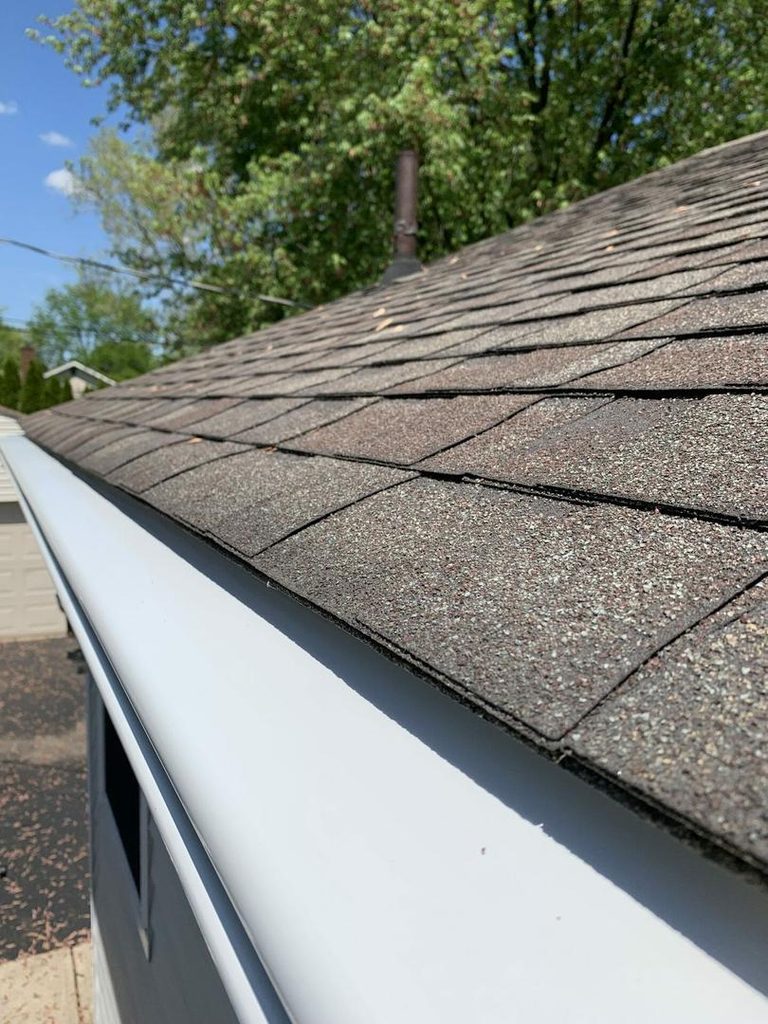 Close view of a K-Guard hooded gutter running along the shingle edge of a Central Ohio roof, with the hood sitting below the shingle course