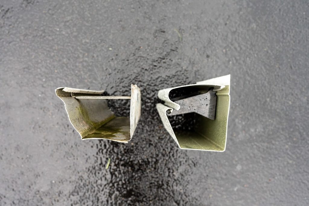 Two K-Guard high-impact polymer gutter hangers photographed on a dark background